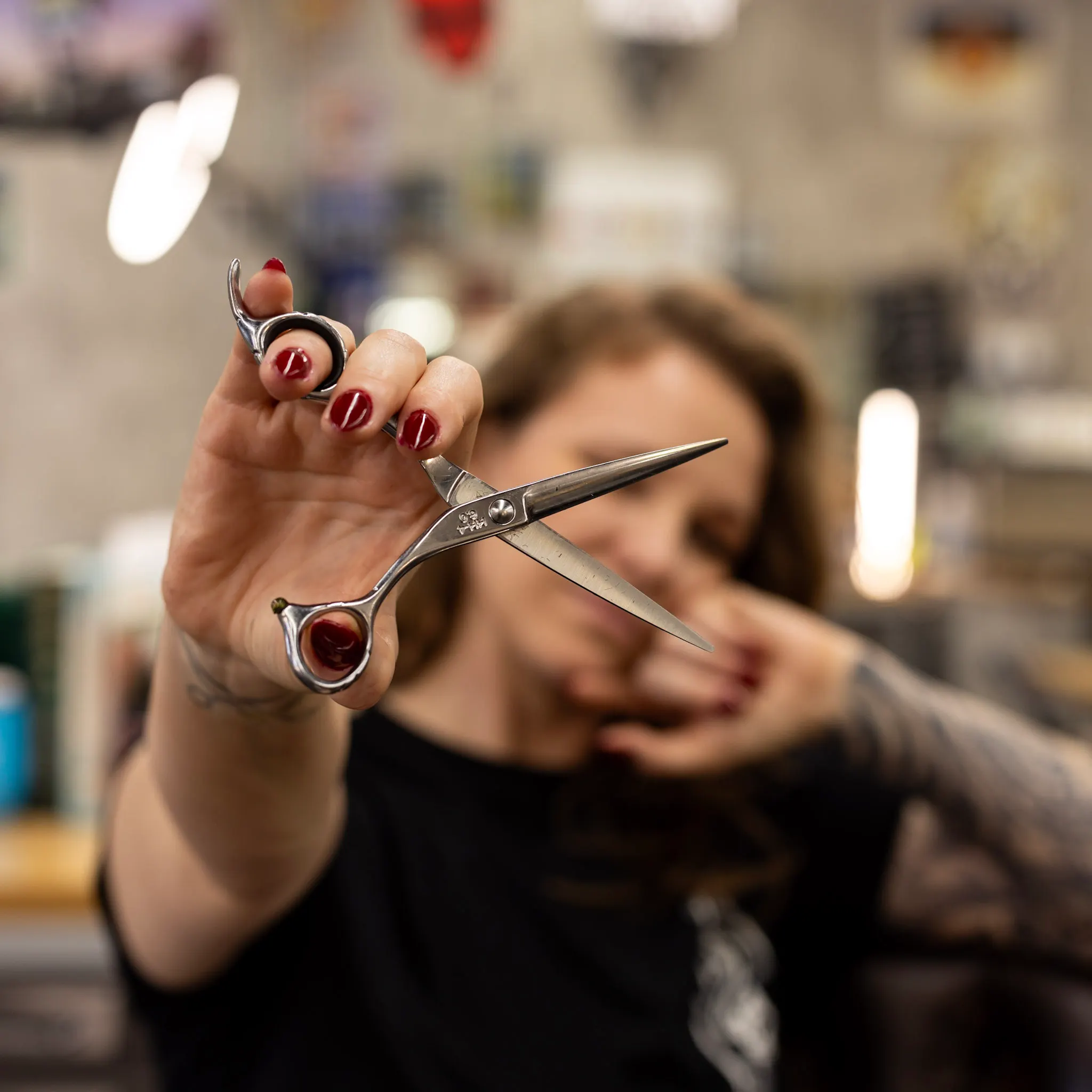 Courtney holding up her shears at Ecdysis Barbershop